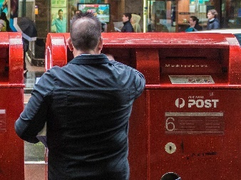 A man posting an envelope in a post box.